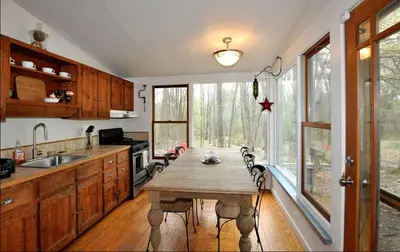 a kitchen with a wooden table and a large window at Idyllic Getaway Cottage in the Woods near Woodstock, New York in Woodstock