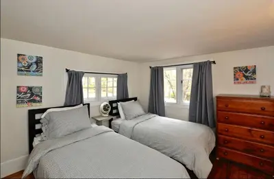 a bedroom with two beds and a dresser and windows at Idyllic Getaway Cottage in the Woods near Woodstock, New York in Woodstock