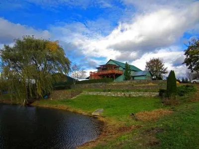 a house sitting on top of a hill next to a river at Pet-Friendly Cottage in a Working Farm near Hudson, New York in Hudson