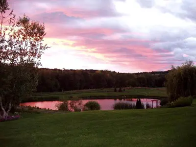 a pond in a field with a sunset in the sky at Pet-Friendly Cottage in a Working Farm near Hudson, New York in Hudson