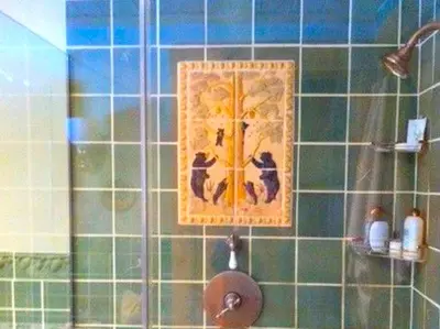 a tile bathroom with a painting of two cats on the wall at Cozy Log Cabin with a Private Hot Tub near Beartown State Forest, Massachusetts in Monterey
