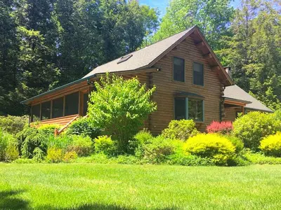 a wooden house with a lawn in front of it at Cozy Log Cabin with a Private Hot Tub near Beartown State Forest, Massachusetts in Monterey