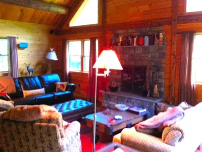 a living room with couches and a fireplace at Cozy Log Cabin with a Private Hot Tub near Beartown State Forest, Massachusetts in Monterey