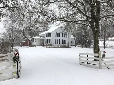 a white house with a fence in the snow at Enchanting Secluded Cabin Rental near Salem, New York in Salem