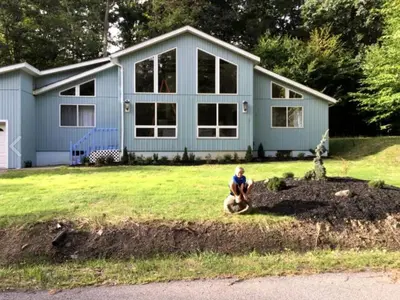 a woman sitting in front of a house at Delightful Cottage Rental with Scenic Views near the Poconos, Pennsylvania in Tobyhanna