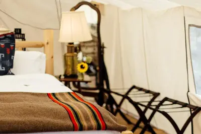 a bedroom with a bed and a table with a lamp at Stylish Camping Tents Set on an Organic Farm in Hudson Valley, New York State in Ghent