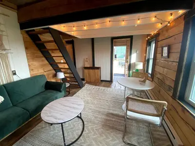 a living room with a green couch and a table at Lovely Farmhouse Cabin with Incredible Landscape Views in New York in Worcester