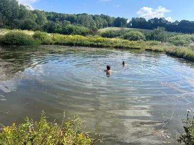two people are swimming in a river at Lovely Farmhouse Cabin with Incredible Landscape Views in New York in Worcester