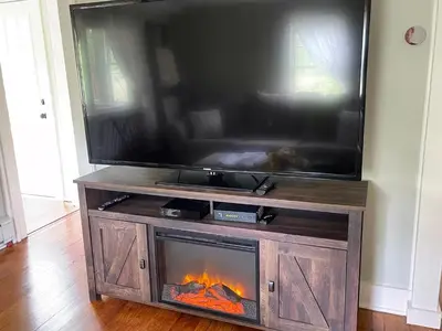 a fireplace in a entertainment center with a flat screen tv at The Red Country Cottage in Amenia