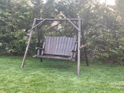 a wooden swing sitting in a field of grass at Hoppy Hill Farm House in Dover Plains