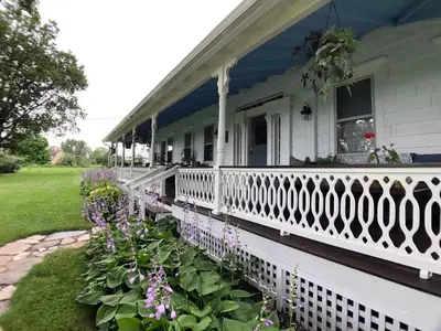 a white house with a white fence and flowers at Hoppy Hill Farm House in Dover Plains