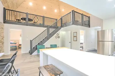 a kitchen and living room with a staircase in a house at The Hut House 3BR 3BA Game Room Massage Chair in Lake Ariel