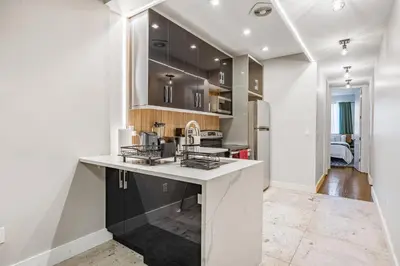 a kitchen with black cabinets and a white counter top at Mid-Century Stay 5BR and 5 Baths w PS5 & Laundry in Brooklyn