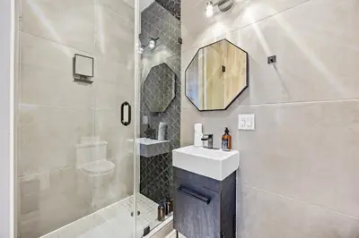 a bathroom with a shower and a sink and a mirror at Mid-Century Stay 5BR and 5 Baths w PS5 & Laundry in Brooklyn