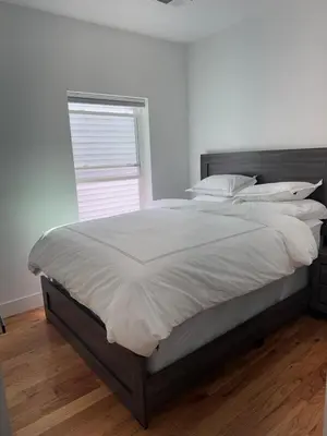 a bedroom with a large bed with white sheets and a window at Cozy 3BR Retreat with Rooftop Near EWR & NYC Access in Newark