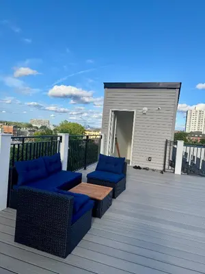 a deck with blue chairs and a table and a building at Cozy 3BR Retreat with Rooftop Near EWR & NYC Access in Newark