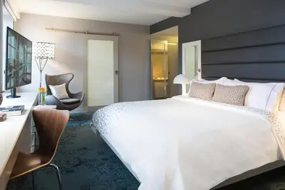 a bedroom with a large white bed and a desk and chair at Renaissance Albany Hotel in Albany