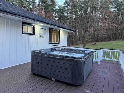 a hot tub sitting on a deck next to a house at Modern getaway in Catskills in Cairo