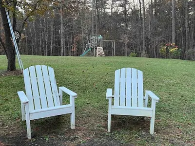 two white chairs sitting in a field with a playground at Modern getaway in Catskills in Cairo