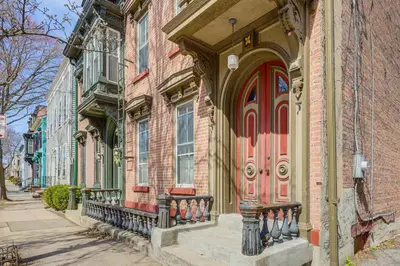a brick building with a red door on a street at 1 Mi to Dtwn Schenectady Apt in Stockade District in Schenectady