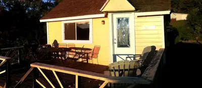 a house with a deck with tables and chairs at Charming Camping Cabin on the Shores of Great Sacandaga Lake in Northville, New York in Northville