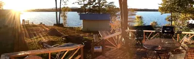 a view of a lake with a grill and a table at Charming Camping Cabin on the Shores of Great Sacandaga Lake in Northville, New York in Northville