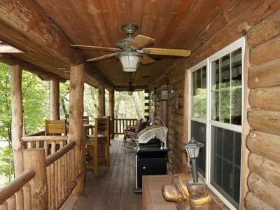 a porch of a log cabin with a ceiling fan at Creekside Log Cabin Rental with Kayaks in Saugerties, New York in Saugerties