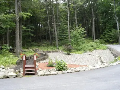 a garden with a bench on the side of a road at Creekside Log Cabin Rental with Kayaks in Saugerties, New York in Saugerties