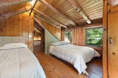 two beds in a room with wooden walls and wooden floors at The Bears Nest in Boiceville