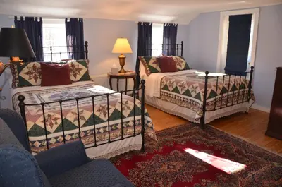 a living room with two beds and a chair at Cornwall Inn in Cornwall Bridge