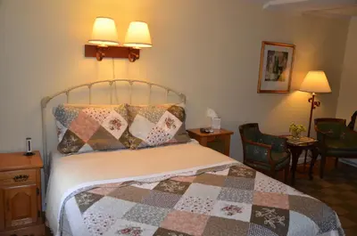 a bedroom with a bed with two lamps and two chairs at Cornwall Inn in Cornwall Bridge
