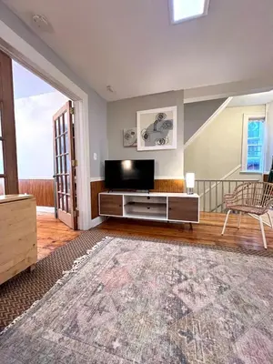 a living room with a flat screen tv on a entertainment center at Ten Minute Commute to NYC in Jersey City