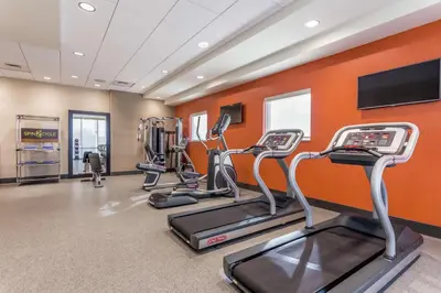 a gym with cardio equipment in a room with orange walls at Home2 Suites by Hilton Albany Airport/Wolf Rd in Albany