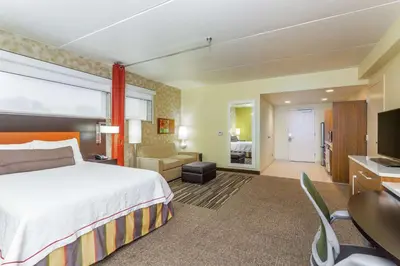 a hotel room with a bed and a living room at Home2 Suites by Hilton Albany Airport/Wolf Rd in Albany