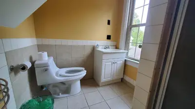 a bathroom with a toilet and a sink and a window at The Empire House Hotel and Restaurant in Gilbertsville
