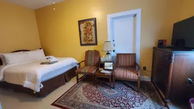 a bedroom with a bed and a table and a chair at The Empire House Hotel and Restaurant in Gilbertsville