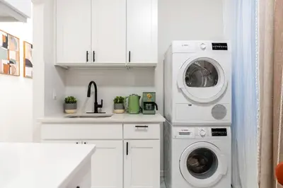 a kitchen with white cabinets and a washer and dryer at Aura Style 3BD Suite at Times Square Manhattan in New York