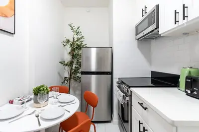 a kitchen with a table and a stainless steel refrigerator at Aura Style 3BD Suite at Times Square Manhattan in New York