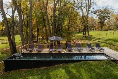 a pool with chairs and an umbrella in a yard at FOUNDERS COTTAGE - 2 room with kitchennete in Kenoza Lake