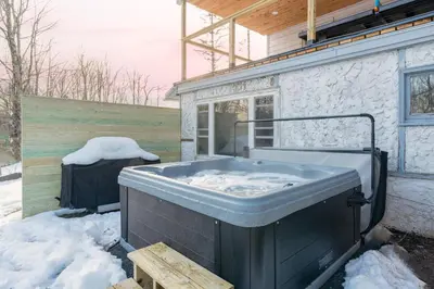 a hot tub sitting outside of a house in the snow at Charming Retreat Walking in Tannersville