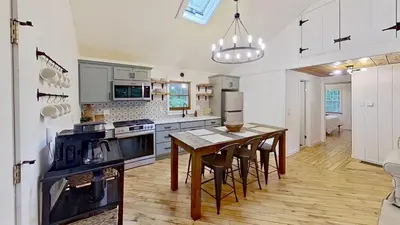 a kitchen with a wooden table and a dining room at Cozy Berkshires Cabin with Lake, Beach, Hot Tub, Fireplace - The Wilde BNB