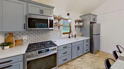 a kitchen with white cabinets and a stove top oven at Cozy Berkshires Cabin with Lake, Beach, Hot Tub, Fireplace - The Wilde BNB