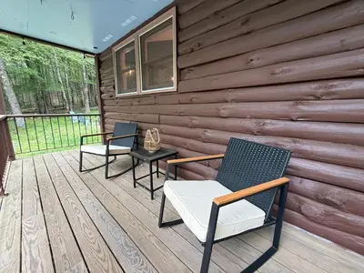 two chairs and a table on a wooden deck at Cozy Berkshires Cabin with Lake, Beach, Hot Tub, Fireplace - The Wilde BNB