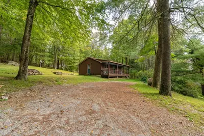 a cabin in the woods with a dirt road in front at Cozy Berkshires Cabin with Lake, Beach, Hot Tub, Fireplace - The Wilde BNB