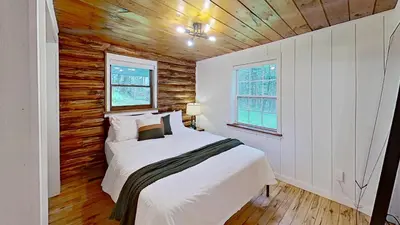 a bedroom with a bed and a wooden wall at Cozy Berkshires Cabin with Lake, Beach, Hot Tub, Fireplace - The Wilde BNB