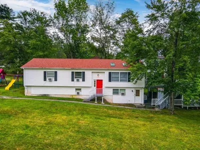 a white house with a red roof and a yard at Catskills Lakefront with Hot Tub, Sauna and Theater in Monticello