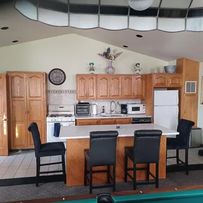 a kitchen with wooden cabinets and a counter with chairs at The Lordship Loft in Stratford