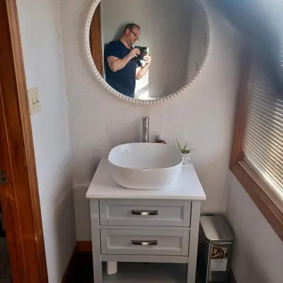 a man taking a picture of a sink in a bathroom at The Lordship Loft in Stratford