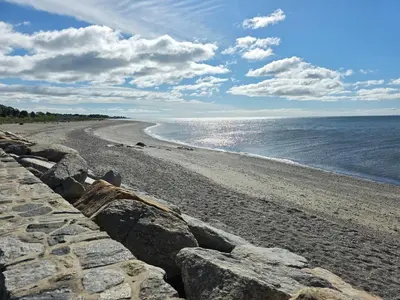 a beach with a stone wall and the ocean at The Lordship Loft in Stratford