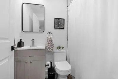 a bathroom with a toilet and a sink and a mirror at Luxury Duplex in Hoboken 15Min to NYC, Fire Pit in Jersey City